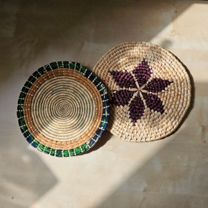 May include: Two woven baskets, one with a green and blue patterned border and the other with a brown star design.