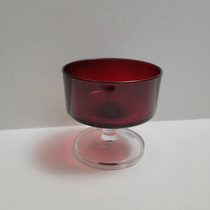 May include: A clear glass stemmed wine glass with a deep red coloured bowl.