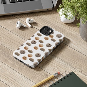 May include: A white iPhone case with a repeating pattern of brown and beige sea urchins. The case has a camera lens cutout and a white background.