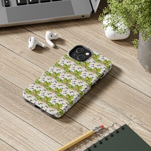 May include: A white phone case with a green four-leaf clover pattern. The case is designed for an iPhone.