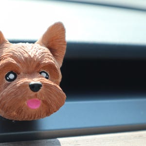 May include: A brown and tan Yorkshire Terrier dog figurine with a pink tongue sticking out. The figurine is made of plastic and has a realistic appearance.