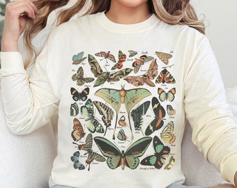 May include: A cream-colored long-sleeved sweatshirt with a vintage illustration of various butterflies and moths. The design features a variety of colors, including green, blue, orange, and brown.