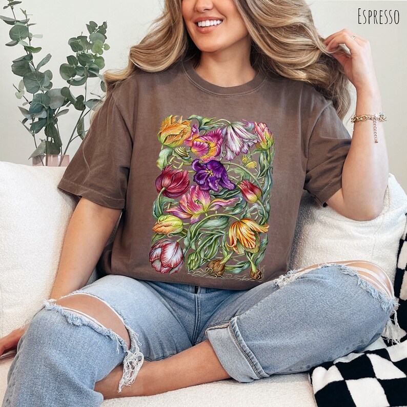 Op de afbeelding: Een bruin T-shirt met een kleurrijke bloemenprint van tulpen. De print bevat een verscheidenheid aan kleuren, waaronder rood, roze, paars, geel en groen.