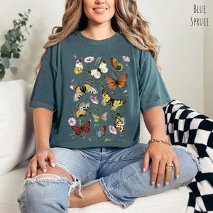 May include: An oversized teal blue t-shirt featuring a printed design of colourful butterflies and flowers. The shirt is made from a soft, comfortable fabric and has a relaxed fit.