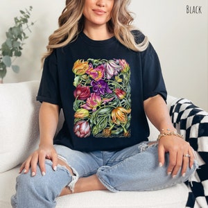 Op de afbeelding: Zwart T-shirt met een kleurrijke bloemenprint van tulpen. De print bevat een verscheidenheid aan kleuren, waaronder roze, paars, geel en oranje.