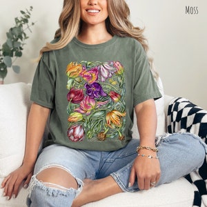 Op de afbeelding: Een groen T-shirt met een kleurrijke bloemenprint van tulpen. De print bevat een verscheidenheid aan kleuren, waaronder roze, paars, geel en oranje.