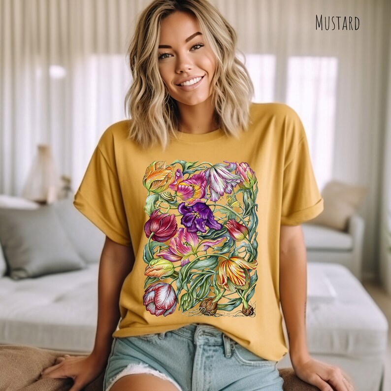 Op de afbeelding: Een mosterdgeel T-shirt met een kleurrijke bloemenprint van tulpen. De print bevat een verscheidenheid aan kleuren, waaronder rood, roze, paars, geel en groen.