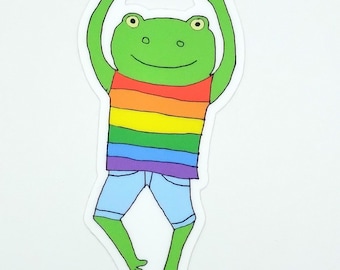 May include: A green frog wearing a rainbow striped shirt and blue denim shorts with its arms raised in the air.