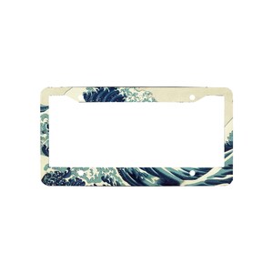 May include: A rectangular license plate frame featuring a printed design of a large, stylized blue ocean wave with white foam crests against a cream-colored background. The frame includes four circular mounting holes at the corners for attachment.