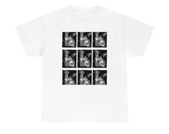 May include: White t-shirt featuring a black and white graphic print of a repeated image of a skull and a figure with wings.
