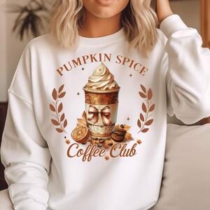 May include: White sweatshirt with a brown and orange graphic of a coffee cup with whipped cream and the text "Pumpkin Spice Coffee Club".