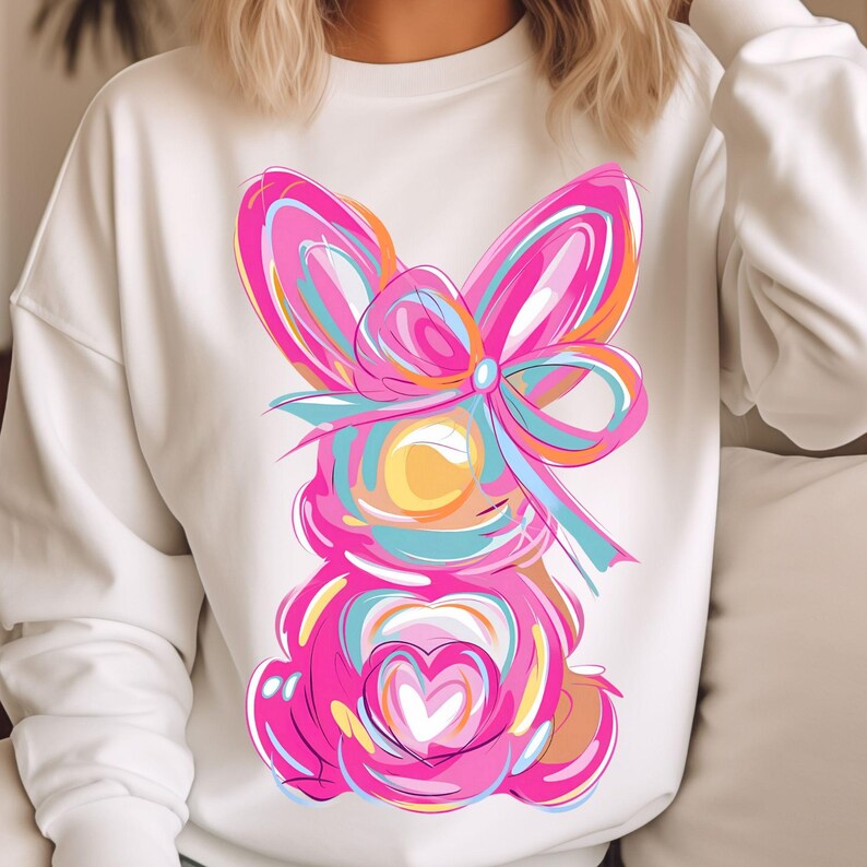 Peut inclure: Sweat-shirt blanc avec un motif abstrait color&eacute; d'un lapin avec un n&oelig;ud. Le lapin est rose, bleu, jaune et orange. Le n&oelig;ud est rose et blanc.