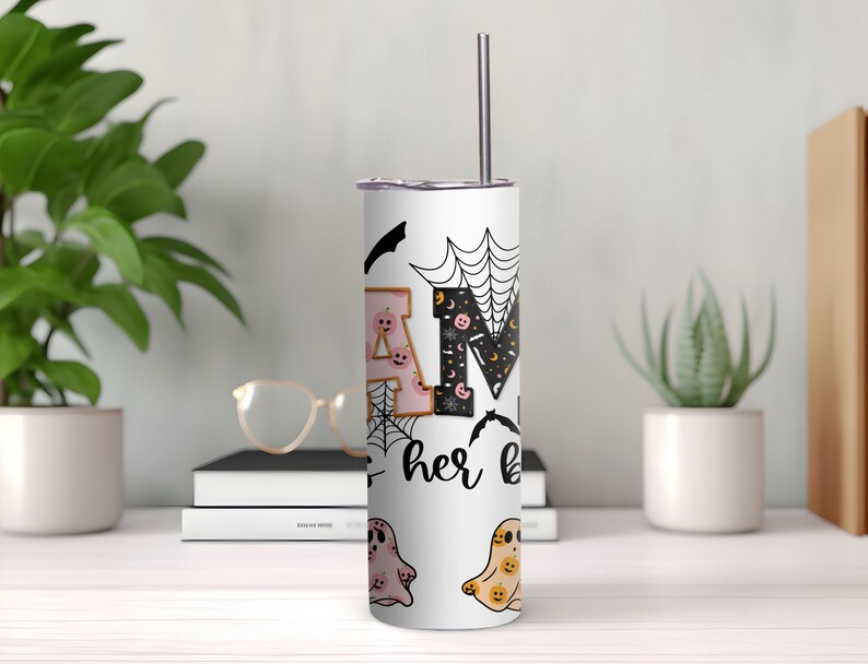 Peut inclure: Un gobelet en acier inoxydable blanc avec un motif sur le th&egrave;me d'Halloween en noir et blanc. Le gobelet pr&eacute;sente les lettres "BOO" avec des fant&ocirc;mes, des chauves-souris et des toiles d'araign&eacute;es. Le texte "her boo" est &eacute;crit sous les lettres.