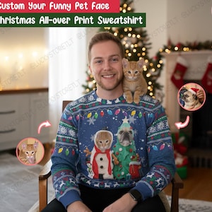 May include: A blue Christmas all-over print sweatshirt with a custom pet face design. The sweatshirt features a cat and a dog dressed as a snowman and a Christmas tree. The text "Custom Your Funny Pet Face" and "Christmas All-over Print Sweatshirt" is visible.