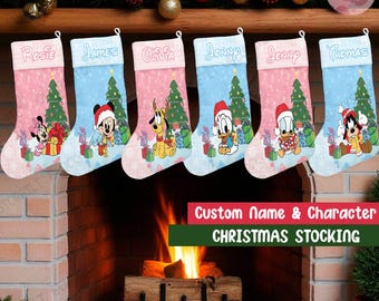 Op de afbeelding: Zes gepersonaliseerde kerstsokken met namen en Disney-personages. Elke kous heeft een ander personage, een kerstboom en ingepakte cadeaus. De kousen zijn roze en blauw met witte bovenkanten. De tekst "Custom Name & Character CHRISTMAS STOCKING" staat onderaan.