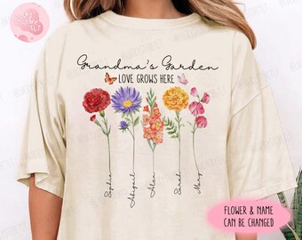 Può includere: Una maglietta beige con il testo "Grandma's Garden Love Grows Here" e un disegno floreale con farfalle. I nomi Sophia, Abigail, Alex, Sarah e Mary sono scritti sotto i fiori.