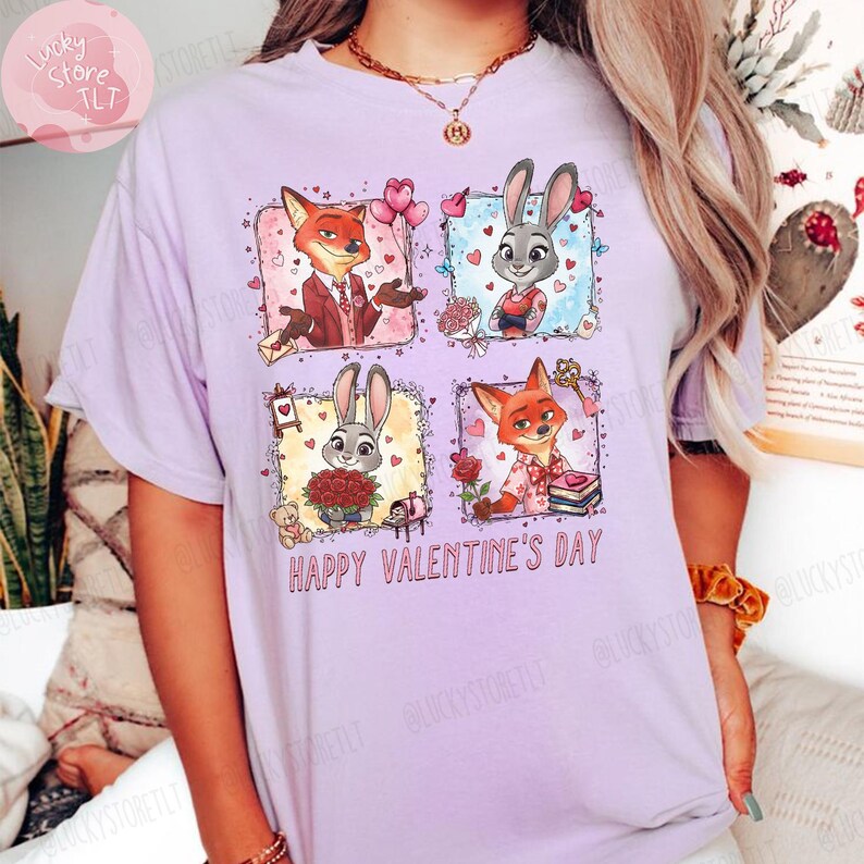 Pu&ograve; includere: T-shirt lilla chiaro con una grafica colorata di personaggi dei cartoni animati in quattro pannelli. Il design include una volpe e un coniglio, con la scritta "HAPPY VALENTINE'S DAY" in rosso. &Egrave; un capo casual.