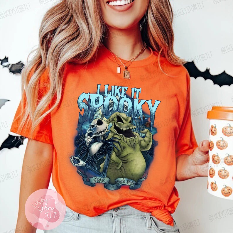 May include: Orange t-shirt featuring a graphic of Jack Skellington and Oogie Boogie from The Nightmare Before Christmas, with the text "I Like It Spooky". The design is in shades of blue, green, and black.