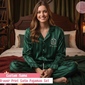May include: Green satin pajama set with vertical black stripes. The pajama top has a crest and the text "Young Spells" embroidered on the chest. The bottom of the image has the text "Custom Name" and "All-over Print Satin Pajamas Set".