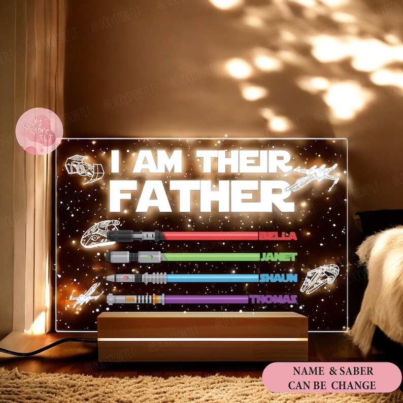 May include: A light-up sign with a black background and white stars. The sign reads "I am their father" with four names and lightsabers below. The names are Bella, Janet, Shaun, and Thomas.
