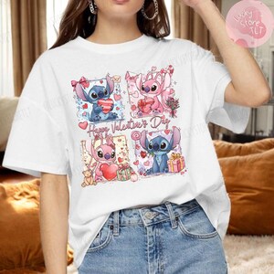 Puede incluir: Camiseta blanca con un gr&aacute;fico colorido que presenta personajes de dibujos animados sosteniendo corazones y regalos. El texto "Happy Valentine's Day" se muestra debajo. El dise&ntilde;o incluye personajes rosas y azules.