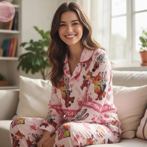 K&ouml;nnte beinhalten: Rosa Pyjama-Set mit Cartoon-Figuren und Herzmustern. Das lang&auml;rmlige Oberteil hat einen Kragen und eine Knopfleiste. Die passende Hose vervollst&auml;ndigt das Set und sorgt f&uuml;r ein bequemes und koordiniertes Nachtw&auml;sche-Ensemble.