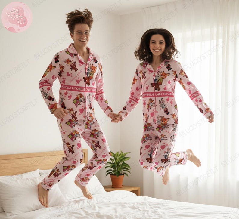 K&ouml;nnte beinhalten: Passende rosa Pyjamas mit Zeichentrickfiguren und Herzen. Die Pyjamas haben lange &Auml;rmel und Hosen. Der Text "CARLY MITCHELL" ist auf Brust und &Auml;rmeln aufgedruckt. Zwei Personen springen auf einem Bett.