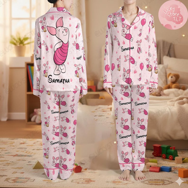 May include: Pink and white pajama set featuring a repeating pattern of a cartoon pig, balloons, and hearts. The pajama top has a button-down front and the name "SAMATHA" printed on it. The pajama pants also have the name "SAMATHA" printed on them.