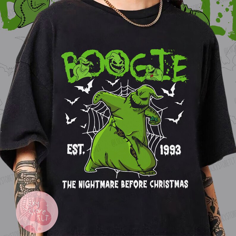 May include: Black t-shirt featuring a green graphic of Oogie Boogie from "The Nightmare Before Christmas." The design includes the word "BOOGIE" in green, the year "1993," and the phrase "THE NIGHTMARE BEFORE CHRISTMAS."