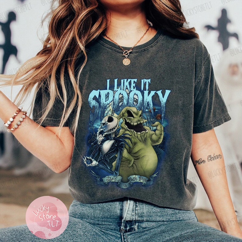 May include: Dark gray t-shirt featuring a graphic of Jack Skellington and Oogie Boogie from The Nightmare Before Christmas, with the text "I Like It Spooky". The design is in shades of blue, green, and white.