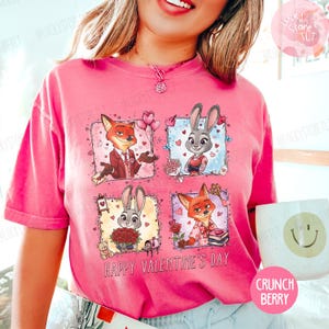 Pu&ograve; includere: T-shirt rosa con personaggi di Zootopia. Il design include Nick Wilde e Judy Hopps in quadrati a tema San Valentino, con la scritta "Happy Valentine's Day".