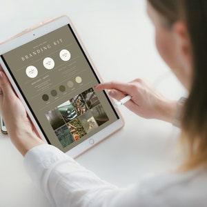 May include: A branding kit displayed on a tablet screen. The kit includes a logo, color palette, and mood board with images of nature and vintage cars. The text on the screen reads "Branding Kit".
