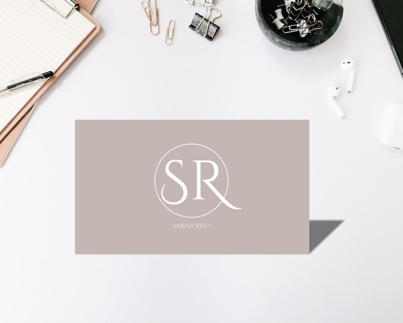 May include: A light brown business card with a white circle containing the letters "SR" and the text "SARAH RILEY" below the circle.