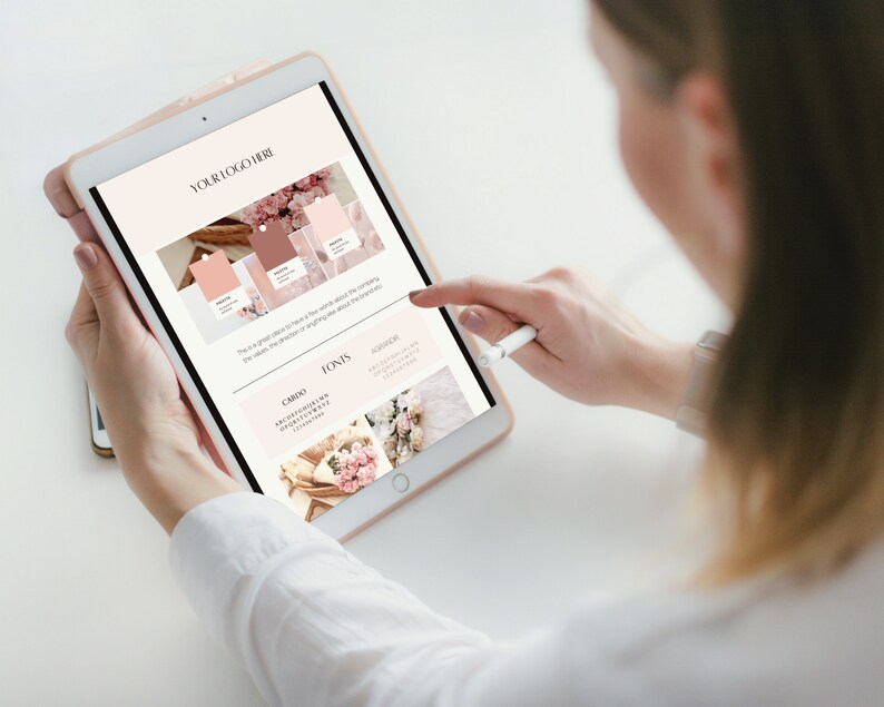 May include: A person using a tablet with a stylus. The tablet displays a branding guide with a logo placeholder, colour palettes, and font examples. The colour scheme includes shades of pink and brown, with floral imagery.