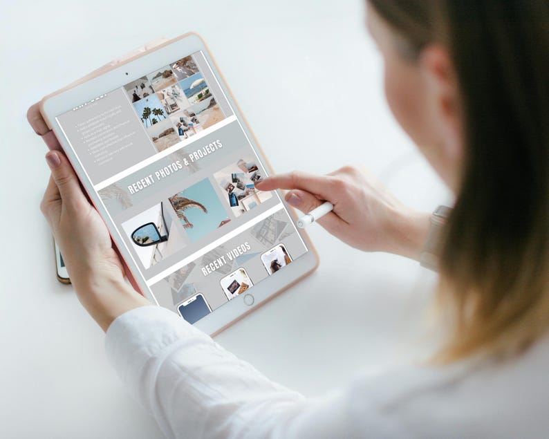 May include: A woman uses a stylus to scroll through a tablet screen displaying a website with a light gray background. The website features a section titled "Recent Photos & Projects" with images of a car, a palm tree, and a beach. Another section titled "Recent Videos" displays thumbnails of videos.