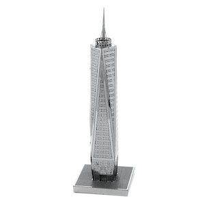 May include: A silver-coloured metal model of a tall skyscraper with a pointed spire. The building has a detailed facade with many small square windows and is mounted on a square base. The model is a miniature representation of a famous landmark.
