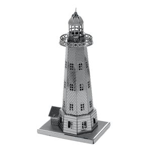 Könnte beinhalten: Ein silbernes Metallmodell eines Leuchtturms. Das Modell hat ein detailliertes Design mit Fenstern, einem Laternenraum und einem kleinen Gebäude. Der Leuchtturm besteht aus ineinandergreifenden Metallteilen und steht auf einer rechteckigen Basis.