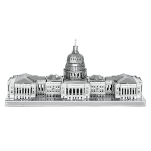 May include: A detailed, silver-colored metal model of a building with a large central dome and multiple rectangular wings. The model features intricate architectural details, including columns, windows, and rooflines. The building is set against a plain white background.