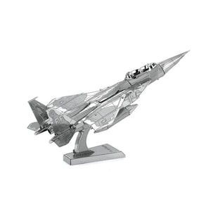 Pode incluir: Um modelo de metal prateado de um caça, exibido em um suporte. O modelo apresenta detalhes intrincados, incluindo o cockpit, as asas e a cauda. O jato está inclinado ligeiramente para cima, dando a impressão de voo. A base é retangular.