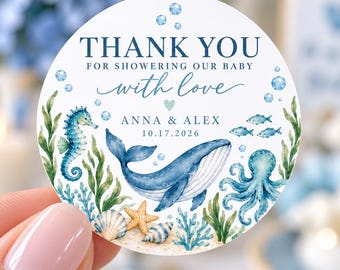 May include: A round sticker featuring a watercolor ocean theme with a blue whale, seahorse, octopus, starfish, and seashells. The text reads THANK YOU FOR SHOWERING OUR BABY with love, ANNA & ALEX, and the date 10.17.2026 in blue font.