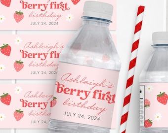 May include: Pink and white water bottle labels with a strawberry and flower design. The labels say "Ashleigh's Berry First Birthday" and "July 24, 2024".