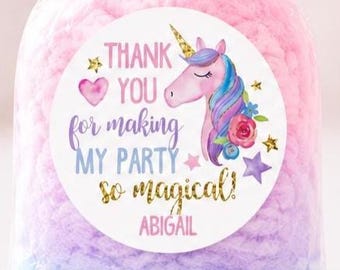 May include: A clear plastic bag filled with pink and blue cotton candy, tied with a shimmering iridescent ribbon. A circular white sticker on the front features a unicorn illustration, gold stars, and the text: THANK YOU for making MY PARTY so magical! ABIGAIL.