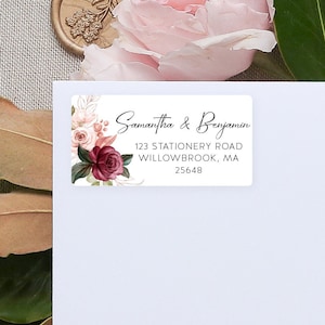 May include: A white envelope with a floral return address label. The label features a burgundy and pink floral design with the text "Samantha & Benjamin, 123 Stationery Road, Willowbrook, MA 25648".