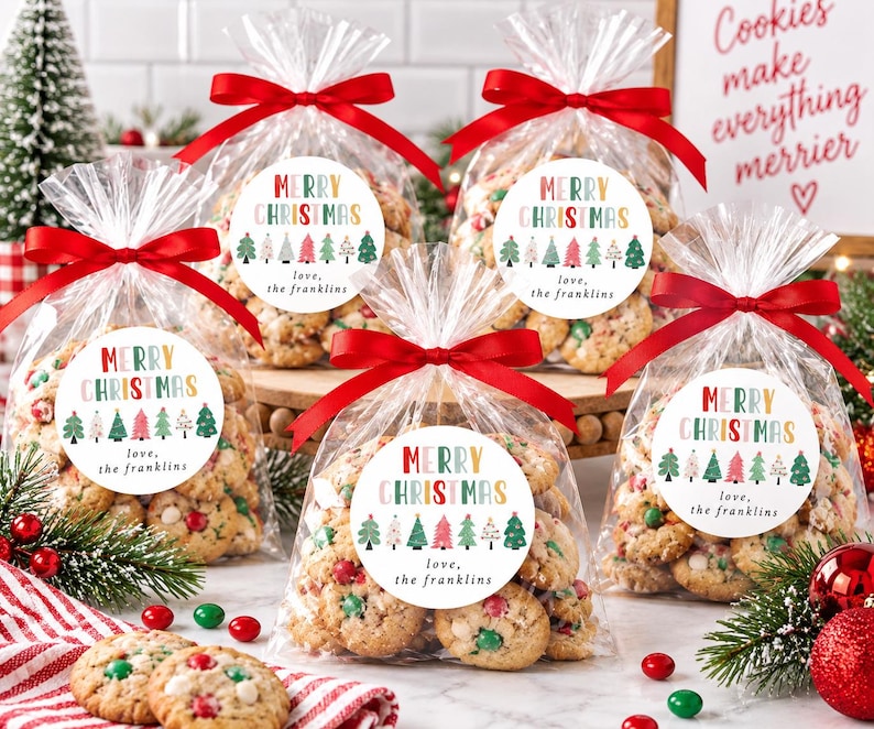 May include: Five clear plastic bags filled with cookies, each tied with a red satin ribbon. A round white sticker on each bag features the text Merry Christmas in colorful letters, a row of illustrated Christmas trees, and the text love, the franklins.