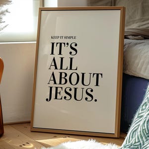 K&ouml;nnte beinhalten: Gerahmter Druck mit dem Text "KEEP IT SIMPLE IT'S ALL ABOUT JESUS." Der Druck hat einen cremefarbenen Hintergrund und schwarzen Text. Der Rahmen ist aus hellem Holz. Der Druck lehnt an einer Wand auf einem Holzboden.