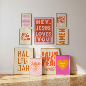 May include: A collection of framed art prints with inspirational quotes and religious messages. The prints feature bold typography in shades of orange, pink, and white against neutral backgrounds. Messages include "Hey Jesus Loves You" and "God is Love."