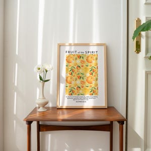 May include: A framed print with a yellow and orange floral pattern and the text "FRUIT of the SPIRIT" in black. The text below the floral pattern reads "But the fruit of the Spirit is love, joy, peace, longsuffering, gentleness, goodness, faith, meekness, temperance." and "GALATIANS 5:22-23".