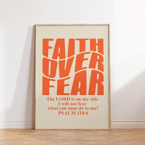 以下が含まれることがあります： オレンジ色の「FAITH OVER FEAR」という文字が書かれた額縁付きのベージュのポスター。その下に「The LORD is on my side I will not fear what can man do to me? PSALM 118:6」という黒文字が書かれている。