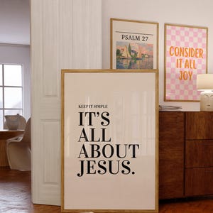 K&ouml;nnte beinhalten: Ein gerahmter Druck mit dem Text "KEEP IT SIMPLE IT'S ALL ABOUT JESUS." wird angezeigt. Zwei weitere gerahmte Drucke sind sichtbar, einer mit einer Landschaft und dem Text "PSALM 27" und ein weiterer mit einem rosa Karomuster und dem Text "CONSIDER IT ALL JOY."