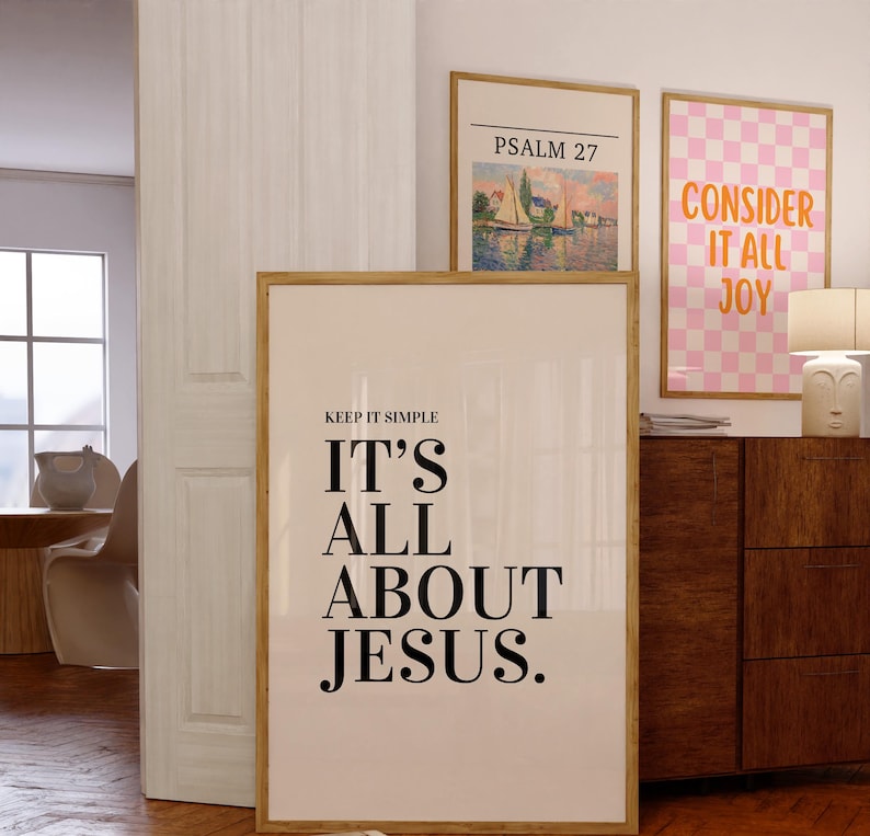 K&ouml;nnte beinhalten: Ein gerahmter Druck mit dem Text "KEEP IT SIMPLE IT'S ALL ABOUT JESUS." wird angezeigt. Zwei weitere gerahmte Drucke sind sichtbar, einer mit einer Landschaft und dem Text "PSALM 27" und ein weiterer mit einem rosa Karomuster und dem Text "CONSIDER IT ALL JOY."